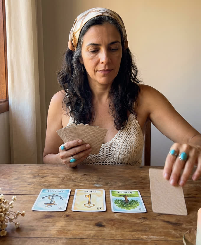 Oraculista da Casa das Cartas abrindo as cartas sobre a mesa, &agrave; luz de lumin&aacute;ria.